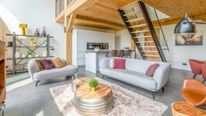 A modern living room with a grey sofa, a wooden coffee table, and a staircase leading to an upper level. - Attractive and Modern 6-person Holiday Villa (De Koog)