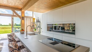 A modern kitchen with a large island, stainless steel appliances, and a view of the outdoors. - Attractive and Modern 6-person Holiday Villa (De Koog)