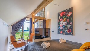 A bedroom with a bed, a TV, a chair, and a painting. - Attractive and Modern 6-person Holiday Villa (De Koog)