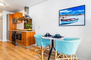 Een moderne keuken met houten kastjes, een ingebouwde oven en een eethoek met twee stoelen.