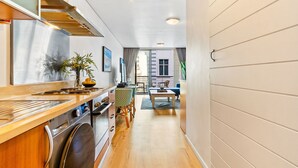 A modern kitchen with a wooden countertop, stainless steel appliances, and a dining area with a table and chairs. - Greenmarket Place 503 (Cape Town)