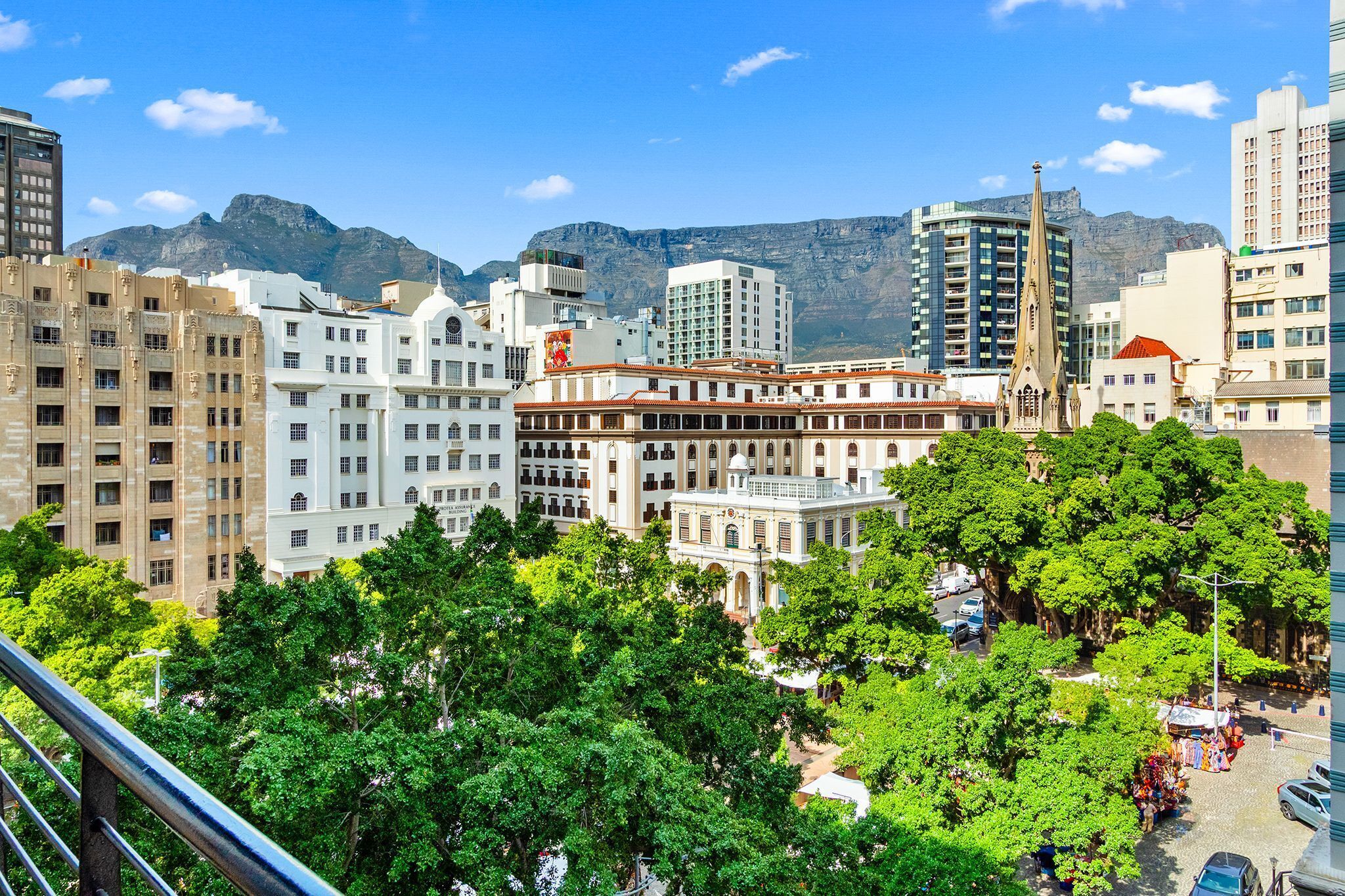 A cityscape with a prominent church, a large white building with a red roof, and a mountain in the background.