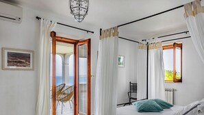 A bedroom with a bed, a chair, a window, and a view of the sea. - Villa Saracena - Seven Bedroom Villa, Sleeps 14 (Costa Saracena - Castelluccio)