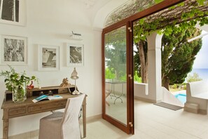 A room with a desk, chair, and a view of a pool and greenery. - Villa Saracena - Seven Bedroom Villa, Sleeps 14 (Costa Saracena - Castelluccio)