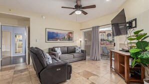 A living room with a gray sofa, a recliner, a flat-screen TV, and a ceiling fan. - Sunlit Oasis Condo w/ Pool & Patio / First Floor (Phoenix)
