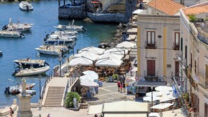 A marina with boats docked, outdoor seating, and a statue in the foreground. - Posidonia - Seven Bedroom Villa, Sleeps 14 (Lipari)