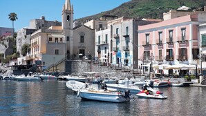 A coastal town with a prominent church tower, a marina with various boats, and buildings with balconies. - Posidonia - Seven Bedroom Villa, Sleeps 14 (Lipari)