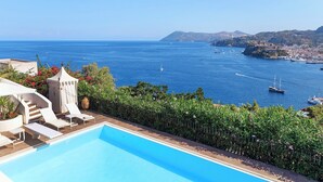A pool with lounge chairs, a view of the sea, and boats. - Posidonia - Seven Bedroom Villa, Sleeps 14 (Lipari)