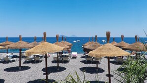 A beach with thatched umbrellas and lounge chairs, a clear blue sky, and boats in the water. - Posidonia - Seven Bedroom Villa, Sleeps 14 (Lipari)