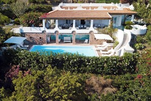 A large house with a swimming pool, outdoor seating, and a stone facade.