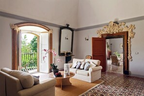 A spacious living room with a sofa, armchair, and a coffee table. There is a large mirror and an ornate doorway. - Villa Armerina - Four Bedroom Villa, Sleeps 7 (Piazza Armerina)