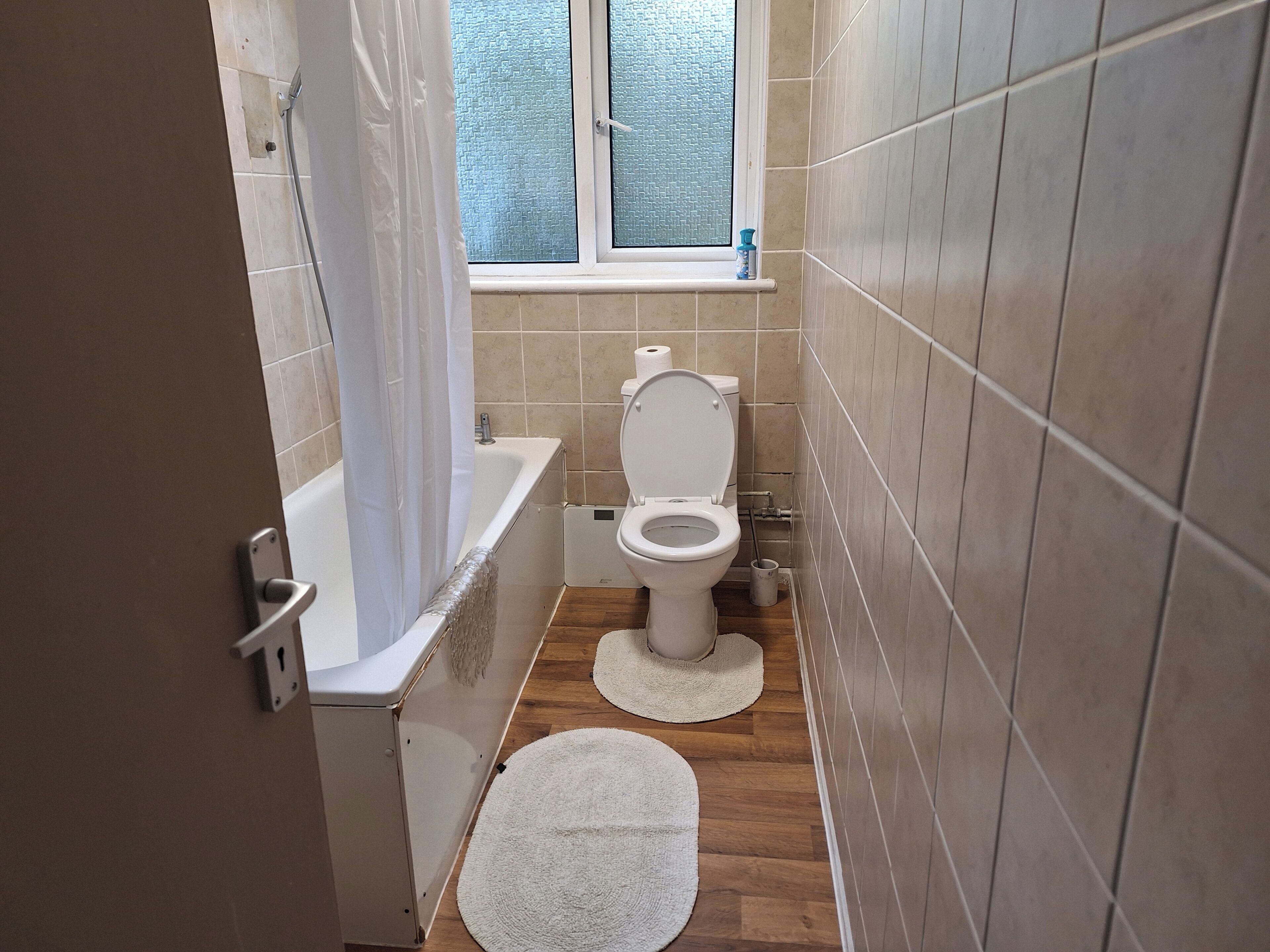 Une petite salle de bain avec des toilettes, une baignoire et une fenêtre.