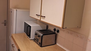 Una kitchenette con microondas, tostadora y encimera de madera.