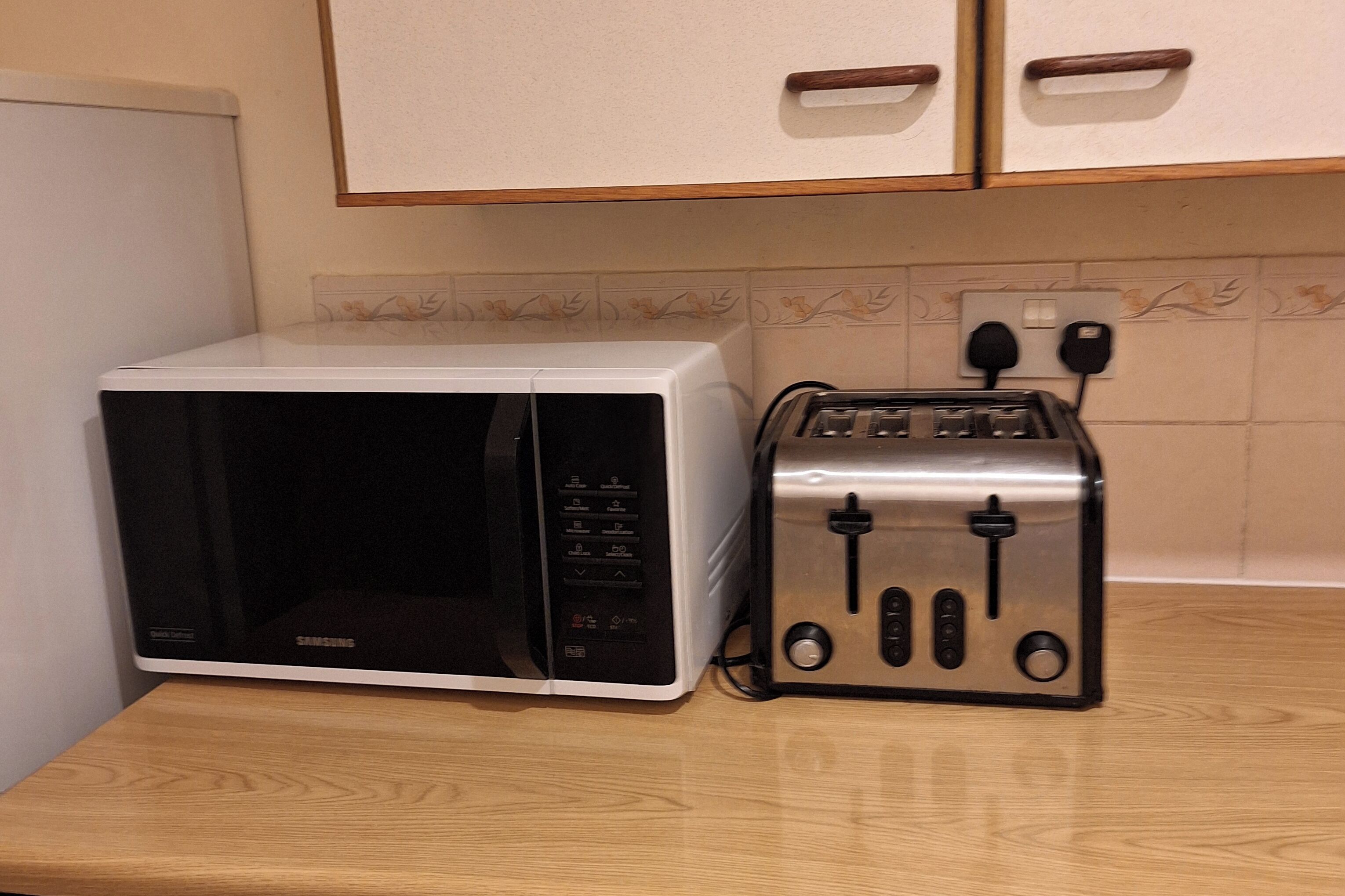 Et køkken med en mikrobølgeovn og en toaster på en træbordplade.