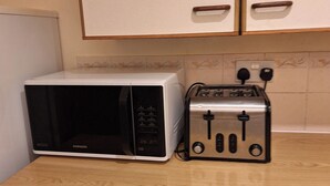 Una cocina con microondas y tostadora sobre una encimera de madera.