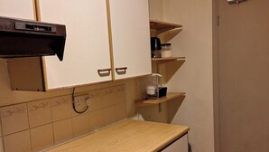 Una cocina con armarios de madera, una encimera y una cafetera sobre una repisa.