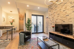 A modern living room with a sofa, coffee table, TV, and a dining area with chairs and a table. - Fasquel Center Apartment (Sevilla)