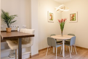 A dining area with a wooden table, four chairs, a vase with flowers, and two framed pictures on the wall. - Fasquel Center Apartment (Sevilla)