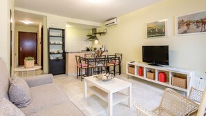 Una sala de estar con sofá, mesa de centro, televisor y un comedor con sillas y mesa.