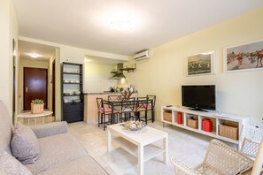 Ein Wohnzimmer mit einer Couch, einem Couchtisch, einem Fernseher und einem Essbereich mit Stühlen und einem Tisch.