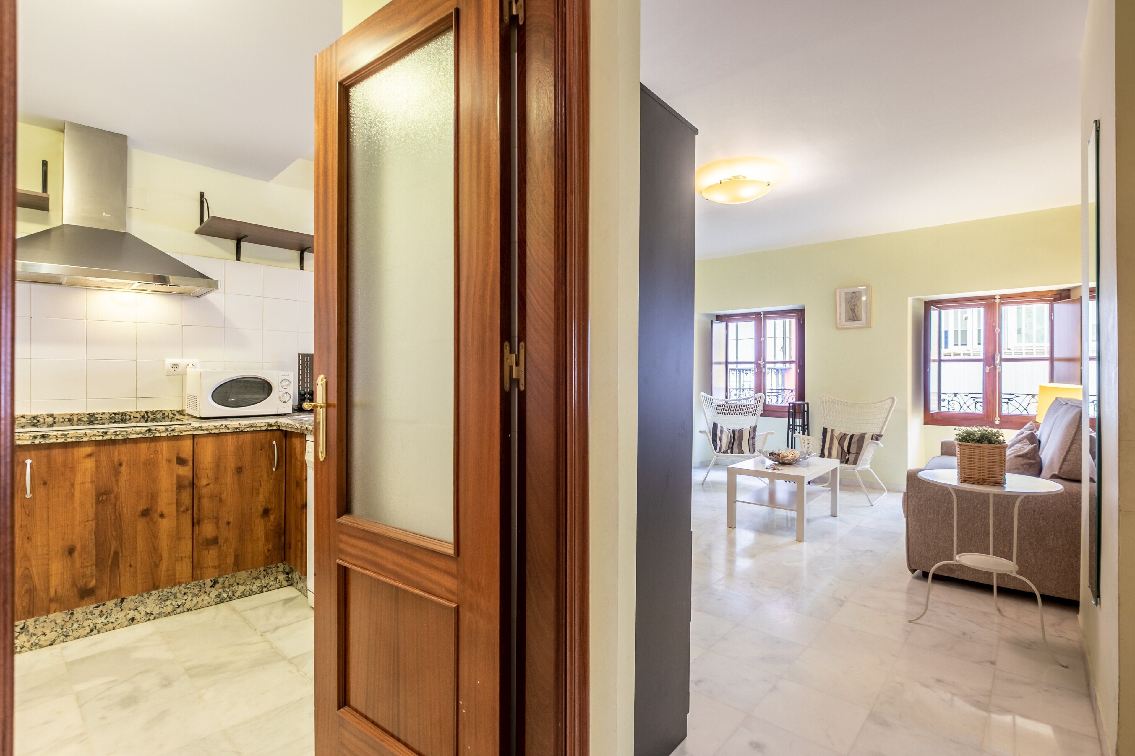 Una cocina con armarios de madera, microondas y una campana extractora de acero inoxidable.
