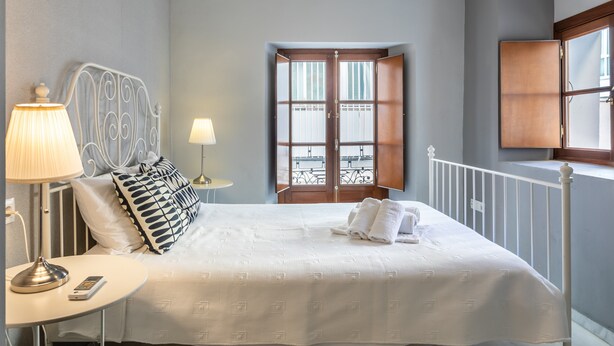 Una habitación de hotel con cama, lámparas de noche, ventana y puerta.