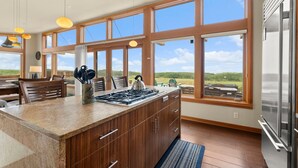 A kitchen with a large island, wooden cabinets, and a view of the outdoors. - Oceanfront Escape in Westport, WA (Westport)