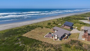 A coastal property with a large house and a smaller building, both featuring modern architecture and a view of the ocean. - Oceanfront Escape in Westport, WA (Westport)