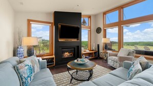 A living room with a fireplace, large windows, and a comfortable seating area. - Oceanfront Escape in Westport, WA (Westport)