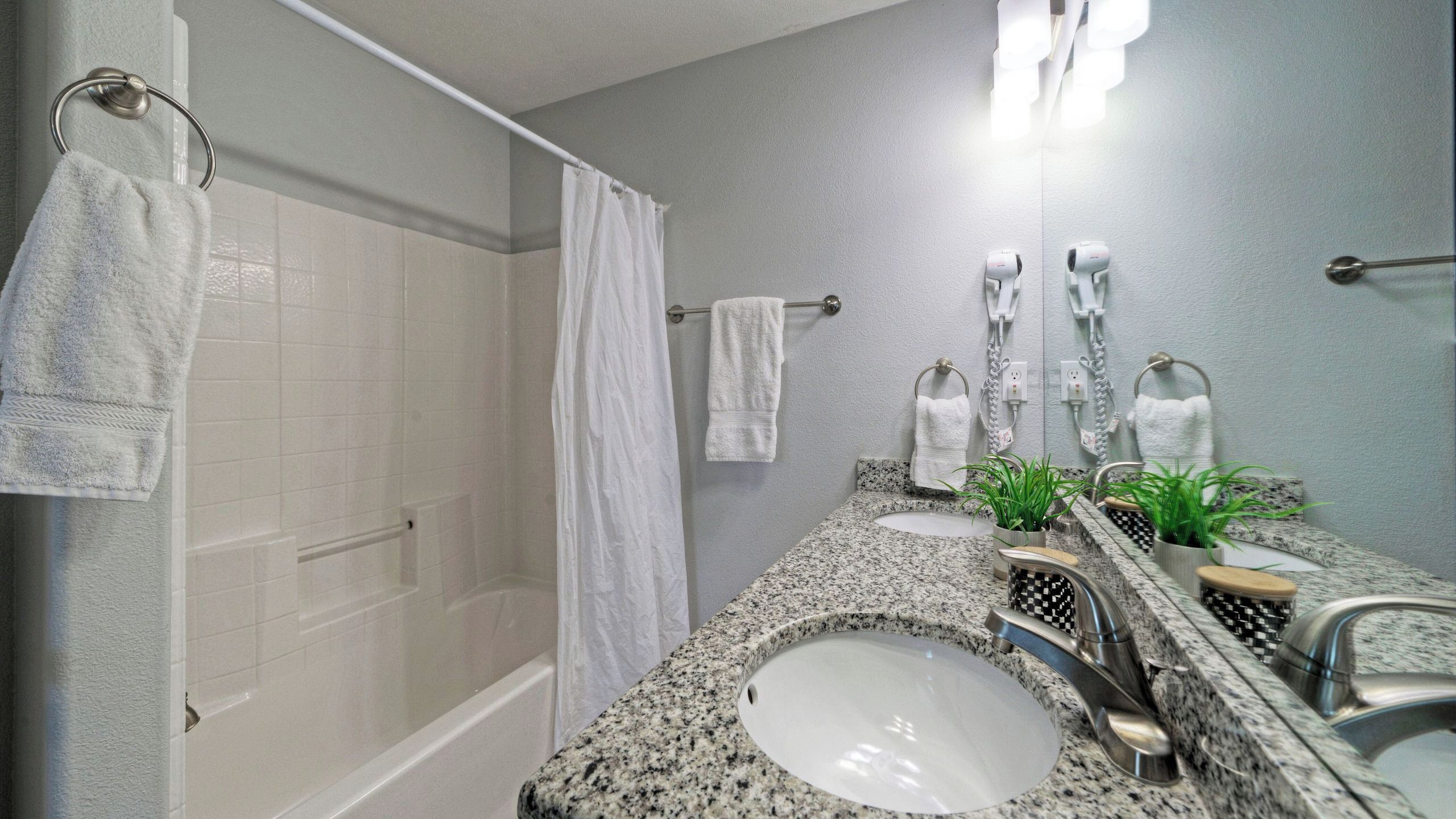 Une salle de bain avec une douche, deux lavabos, un miroir et des porte-serviettes.