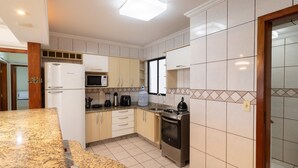 Eine moderne Küche mit weißen Schränken, einer eingebauten Mikrowelle, einem Gasherd und einem Kühlschrank.