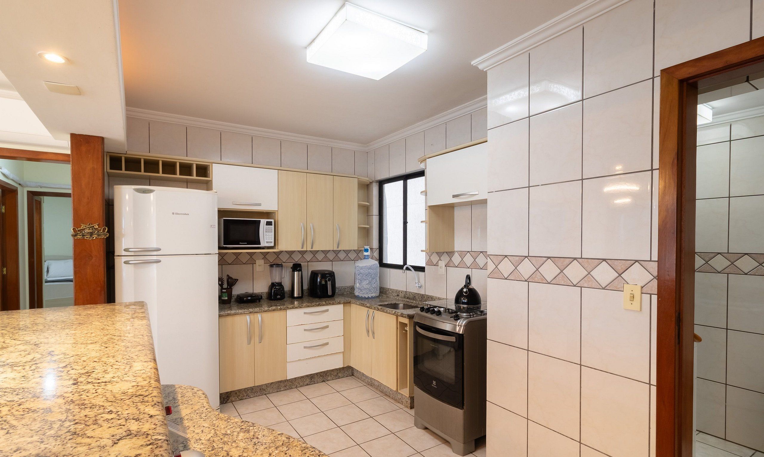 A modern kitchen with white cabinets, a built-in microwave, a gas stove, and a refrigerator.