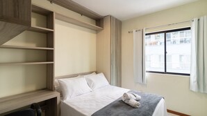 Ein Schlafzimmer mit einem Bett, einem Schreibtisch und einem Fenster.
