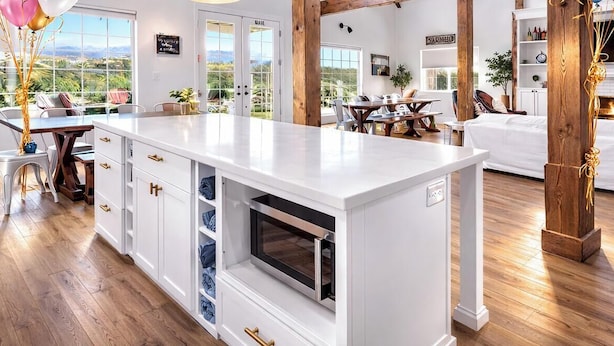A spacious kitchen with white cabinetry, a built-in oven, and a large island. There is a dining area with a wooden table and chairs, and a cozy seating area with a fireplace. - “Country Living” Magazine Home, 5 min To Wineries, Resort Pool. (Temecula)