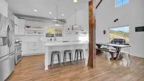 A modern kitchen with white cabinetry, stainless steel appliances, and a central island with stools. - “Country Living” Magazine Home, 5 min To Wineries, Resort Pool. (Temecula)