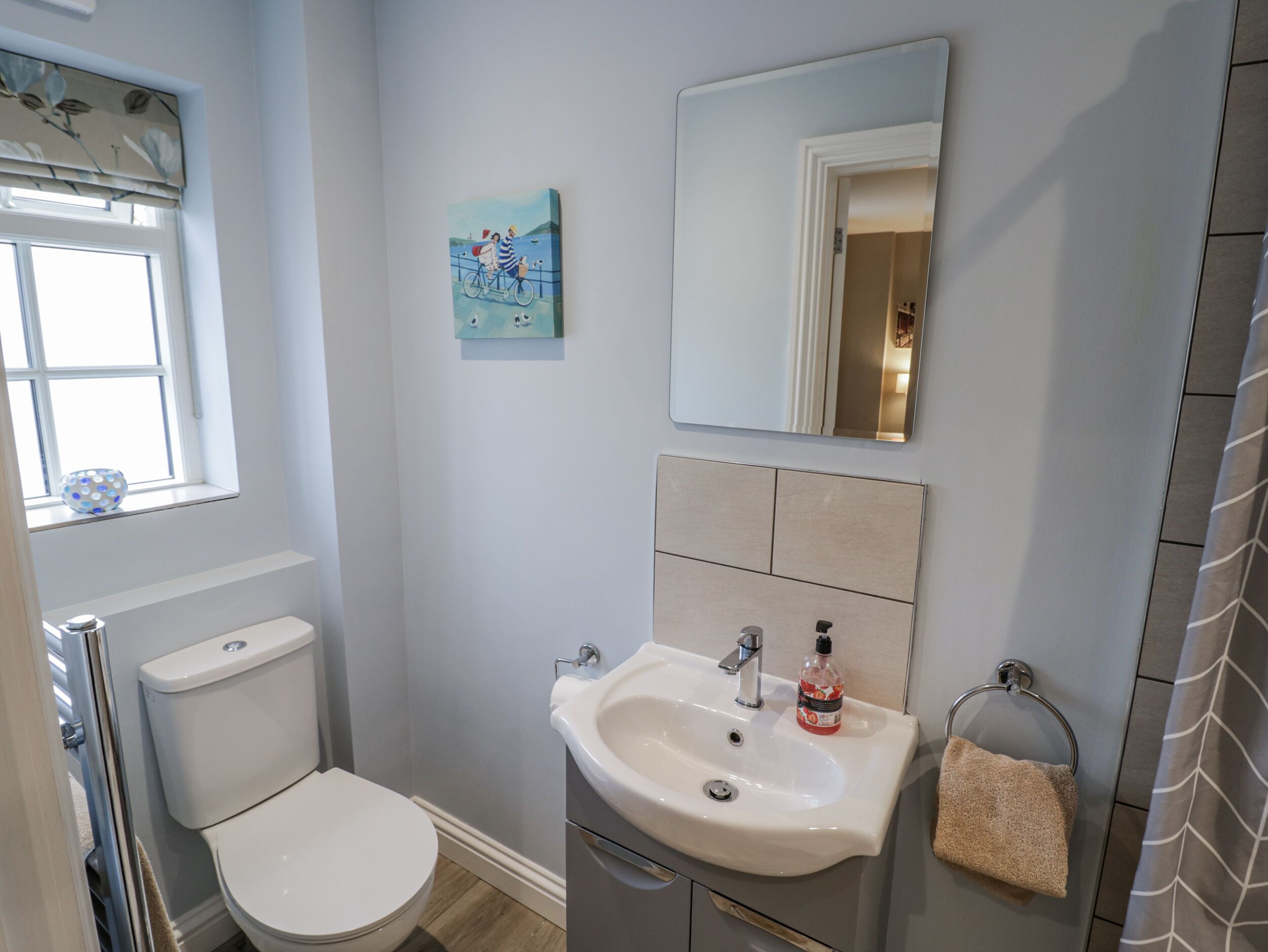 A bathroom with a toilet, sink, and mirror.