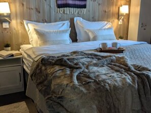 A neatly made bed with a fur throw, a tray with a cup and a book, and a lamp on the nightstand. - Mountain cabin with jacuzzi at Forollhogna - sleeps 12, 1.5 hours from Trondheim (Trøndelag)
