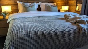 Una habitación con paneles de madera, una cama, dos lámparas de noche y un cuadro en la pared.