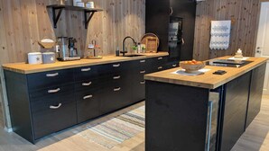 Una cocina moderna con armarios negros, encimera de madera y una isla integrada.