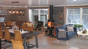 Una sala de estar acogedora con chimenea, paredes de madera y un comedor con sillas y una mesa.