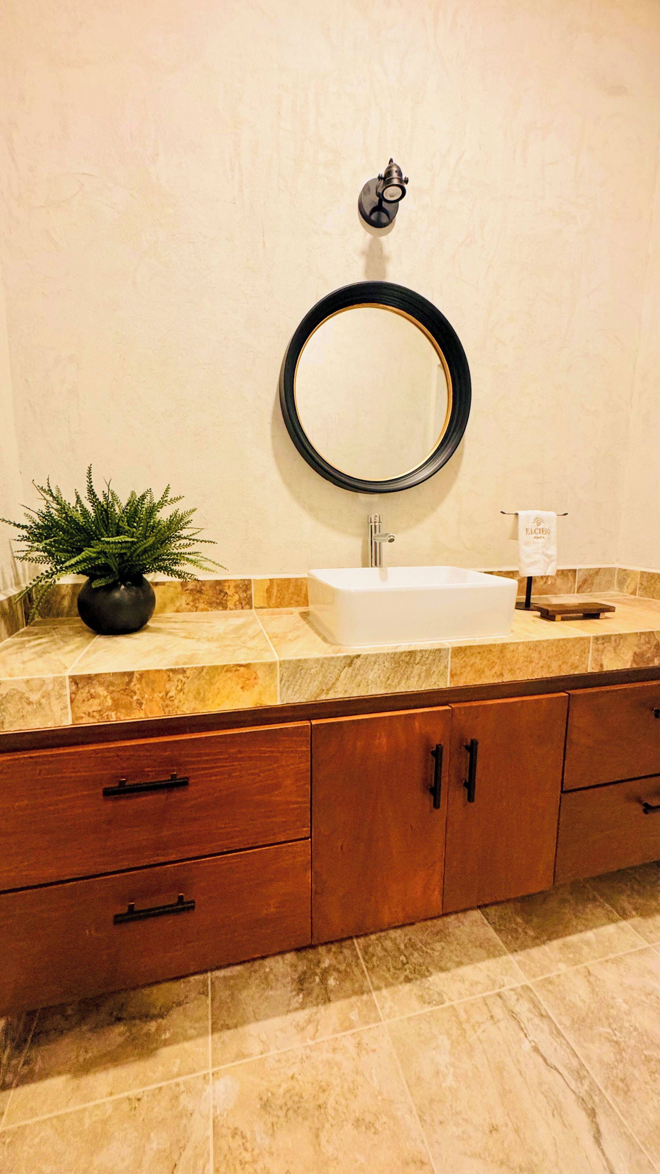 Un baño con lavamanos, espejo y armarios de madera.