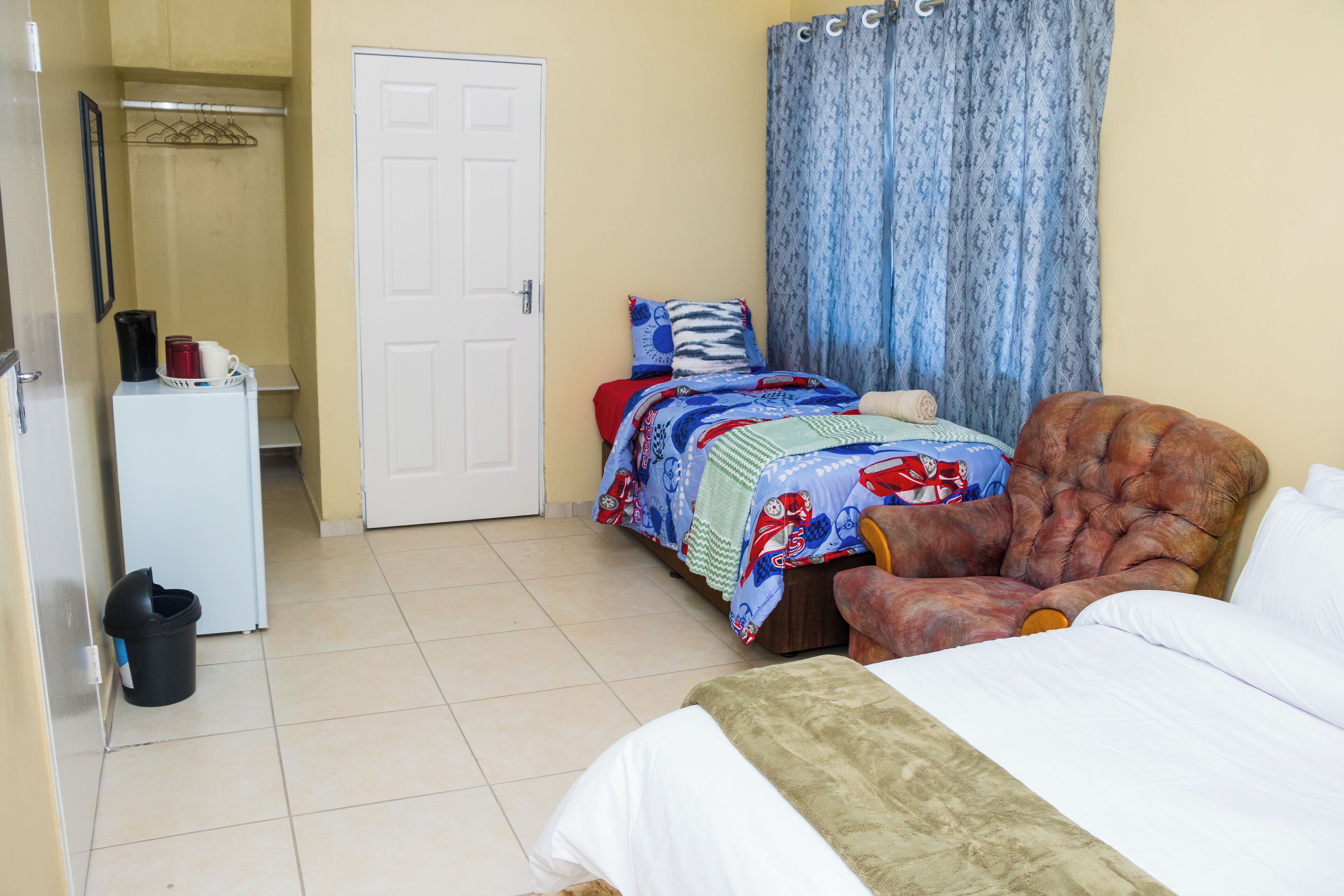 A bedroom with a bed, a chair, a wardrobe, and a door.