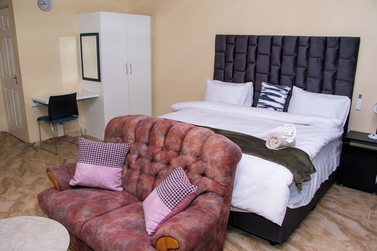 A bedroom with a bed, a chair, a wardrobe, and a desk.