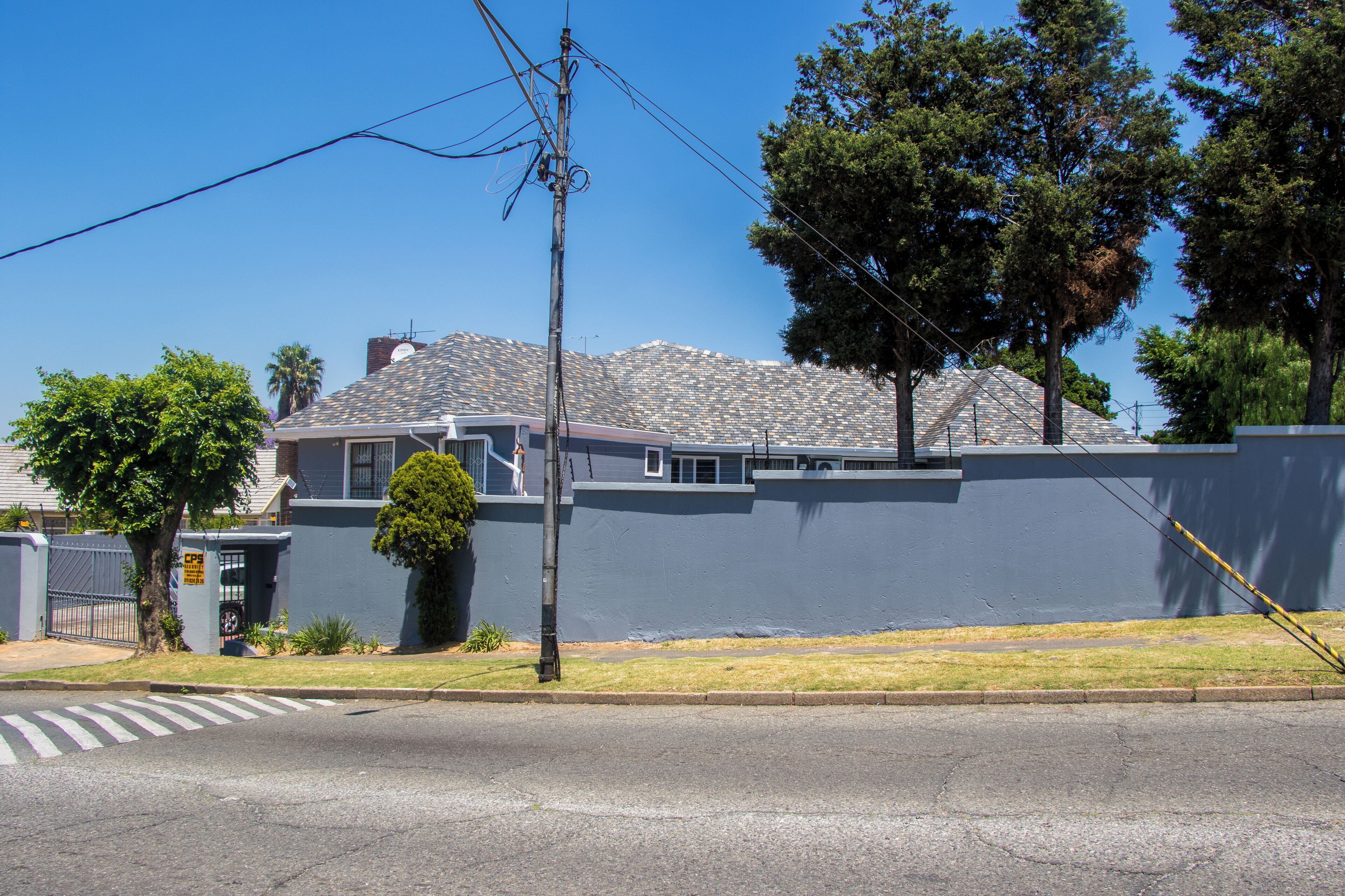 A residential building with a grey exterior, a visible garage door, and a tree in front.
