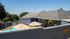 Propiedad residencial con piscina, dos sombrillas y un letrero de seguridad.
