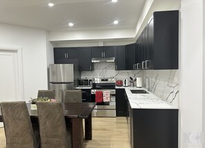 A modern kitchen with dark cabinets, stainless steel appliances, and a marble backsplash. - Modern 3-Bedroom Apartment in Luxury Home in Downtown Richmond Hill (Richmond Hill)
