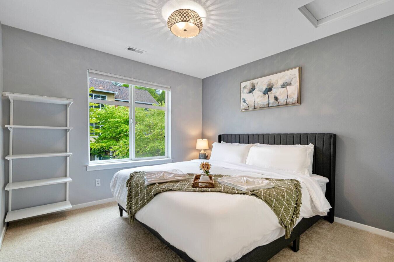 A bedroom with a bed, a window, a ladder, and a ceiling light.