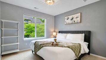 A bedroom with a bed, a window, a ladder, and a ceiling light.