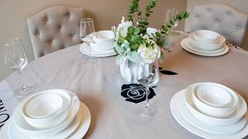 A round table set for a meal with white plates, bowls, and wine glasses.