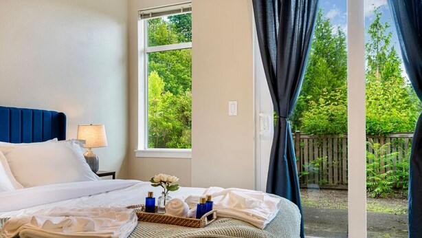 A neatly made bed with pillows, a bedside lamp, and a tray with toiletries.